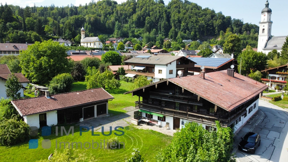 Luftbild des Bauernhauses mit Nebengebäude und Kirchturm im Hintergrund, Kiefersfelden