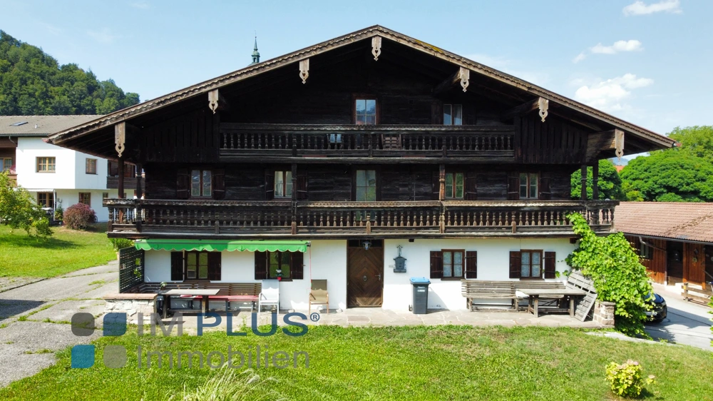 Vorderseite des Bauernhauses mit zwei Holzbalkonen und Sitzbänken, Kiefersfelden