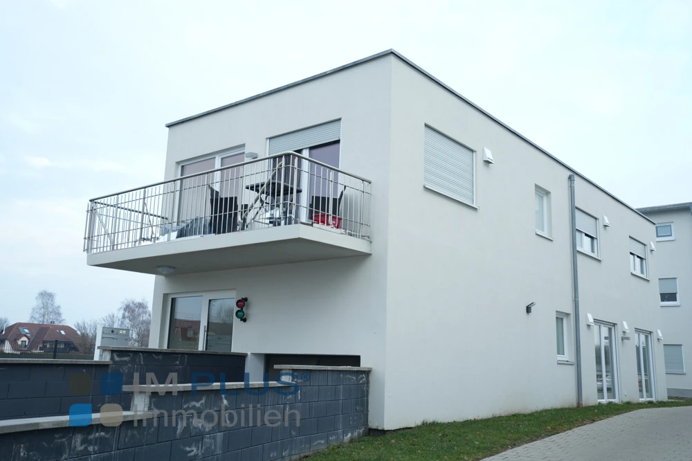 Weißes Mehrfamilienhaus mit Flachdach und Balkon über dem Hauseingang, Dillingen